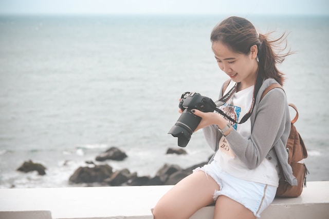 Frau mit Kamera im Urlaub am Strand